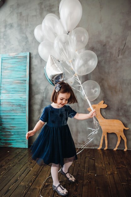 La petite fille garde des ballons dans la chambre