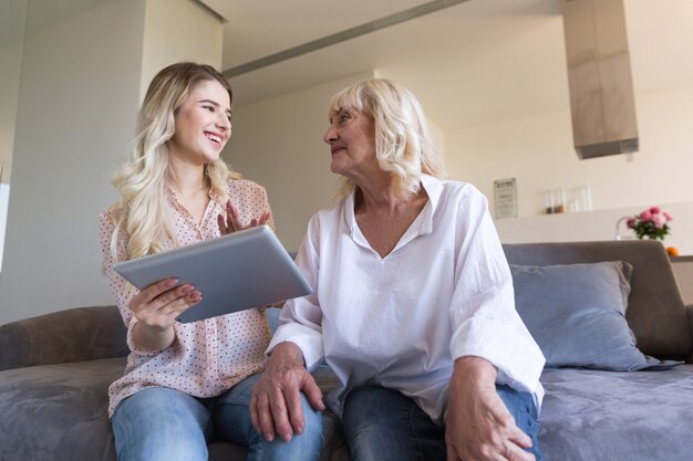 Petite-fille et grand-mère souriante avec tablette pc