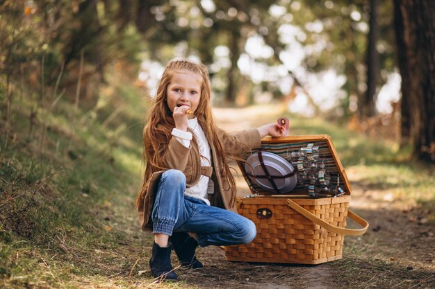 Petite fille avec une grande boîte de pique-nique dans les bois