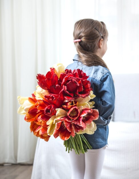 Petite fille avec un gros bouquet de tulipes