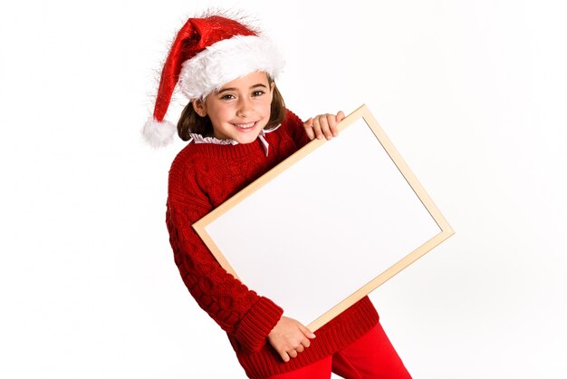 Petite fille habillée en Père Noël tenant un tableau blanc