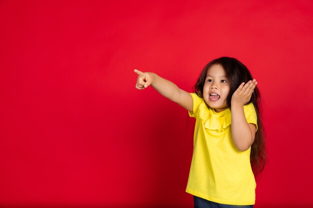 Petite fille isolée sur rouge, heureuse