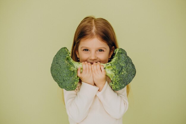 Petite fille isolée tenant du brocoli cru vert