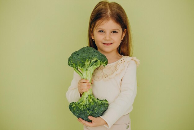 Petite fille isolée tenant du brocoli cru vert