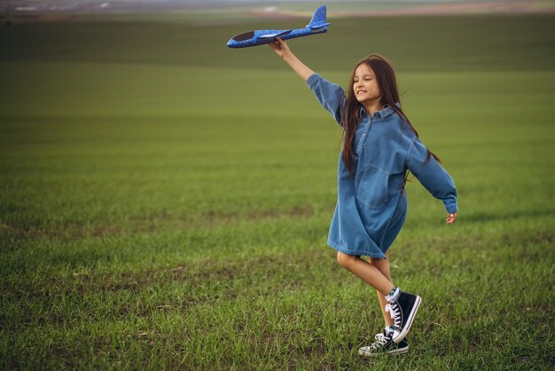 Petite fille jouant avec un avion jouet sur le terrain