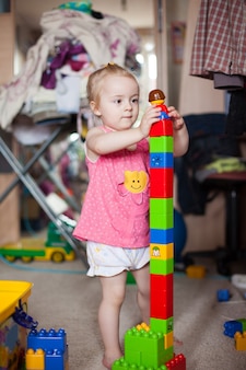 Petite fille jouant avec des blocs de plastique colorés dans un salon
