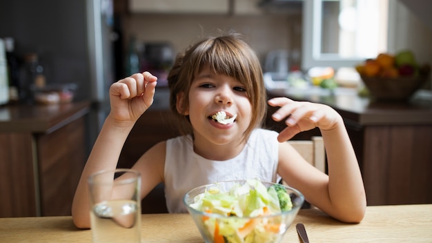 Petite fille jouant avec une salade en mangeant