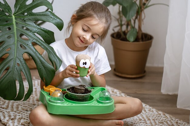 Une petite fille avec un kit bébé pour faire pousser une plante toute seule.