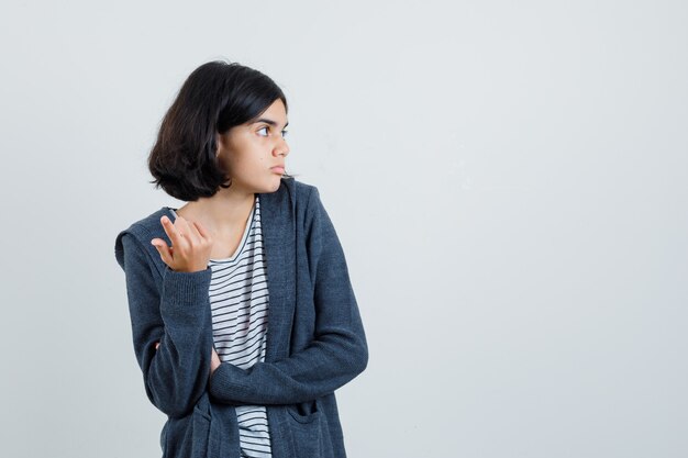 Petite fille levant la main en geste perplexe en t-shirt