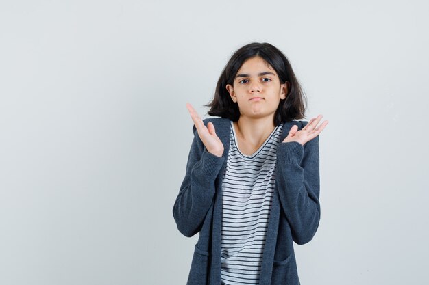 Petite fille levant les mains en geste perplexe en t-shirt