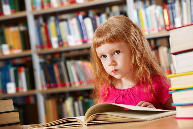 Petite fille lisant dans la bibliothèque