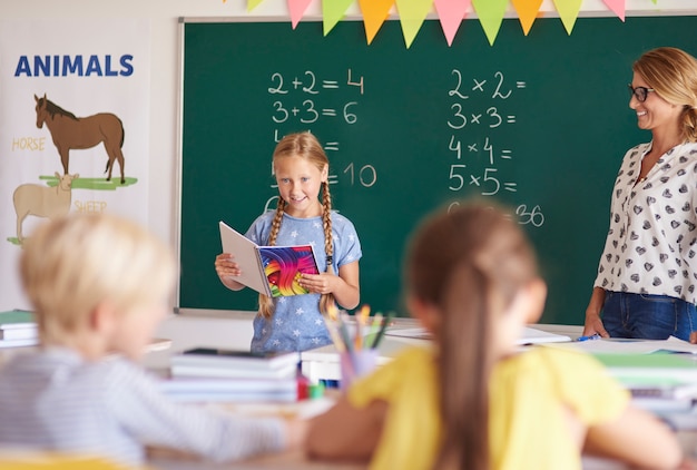 Petite fille lisant ses devoirs dans la salle de classe