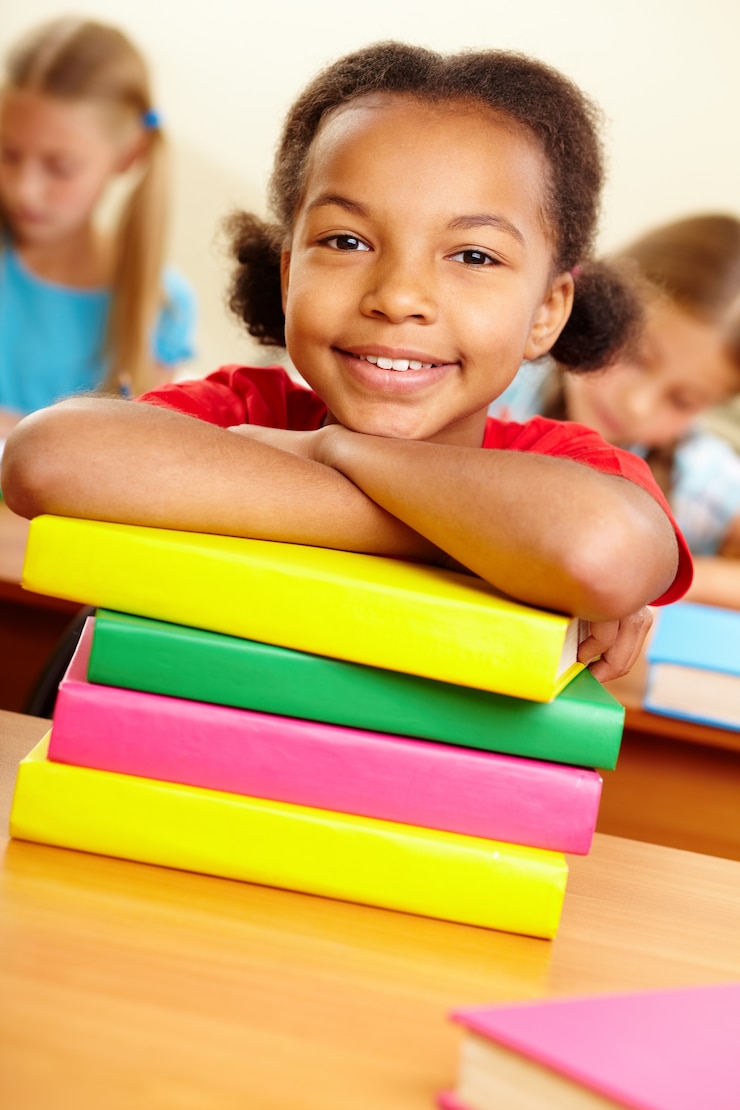 Photo gratuit petite fille avec des livres colorés sur la table