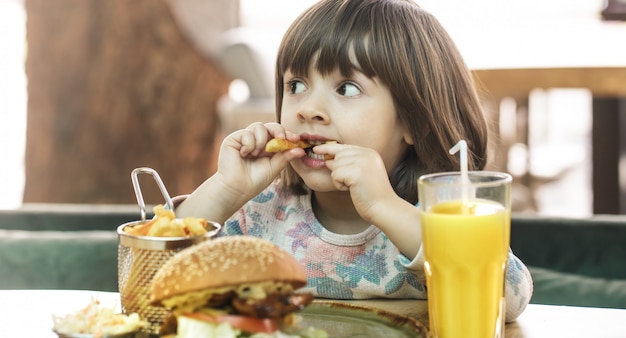 Petite fille mange dans un café de restauration rapide