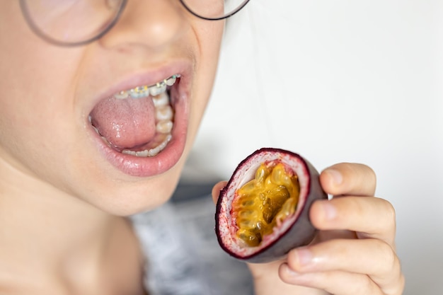 Photo gratuite une petite fille mange du fruit de la passion en gros plan