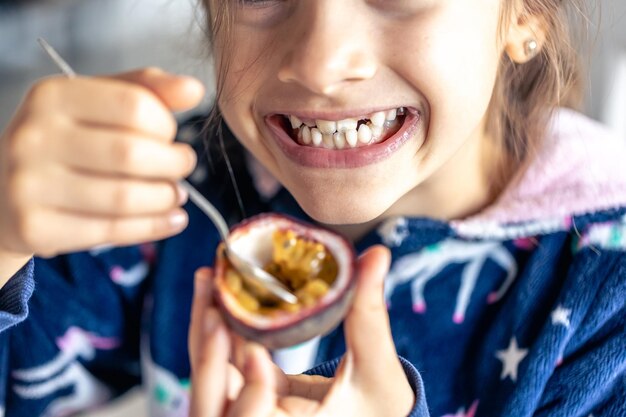 Photo gratuite une petite fille mange du fruit de la passion en gros plan