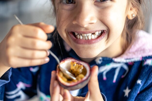 Une petite fille mange du fruit de la passion en gros plan