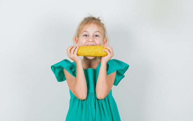 Petite Fille Mangeant Du Maïs En Robe Verte Et à La Joyeuse