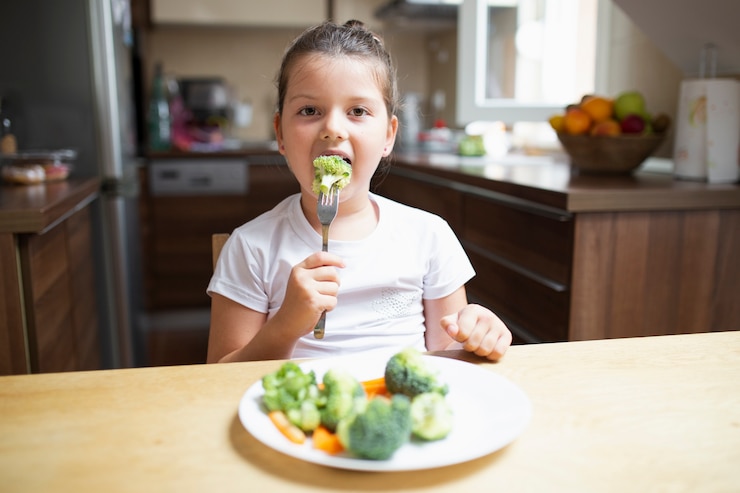 Photo gratuit petite fille mangeant des légumes sains à la maison