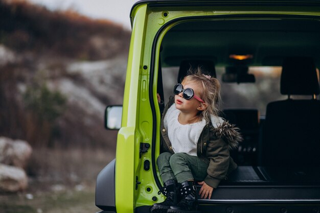 Petite fille mignonne assise à l'arrière de la voiture