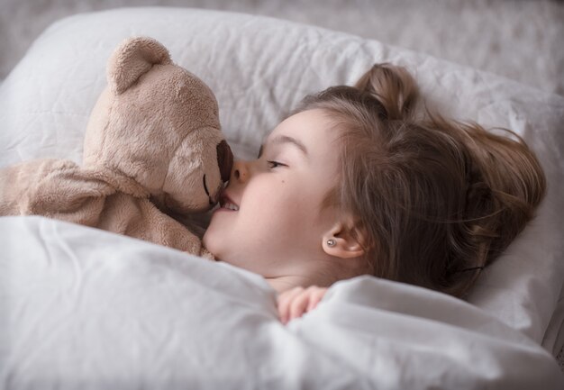 Petite fille mignonne au lit avec jouet