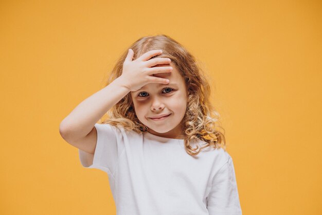 Petite fille mignonne montrant des émotions, d'isolement sur le fond jaune