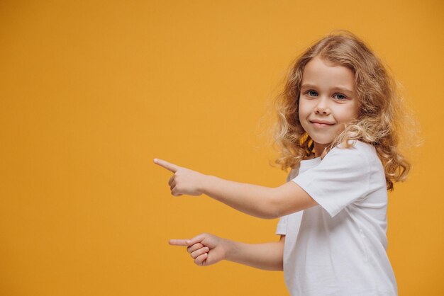 Petite fille mignonne montrant des émotions, d'isolement sur le fond jaune