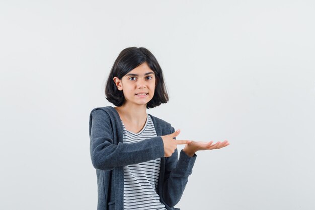 Petite fille montrant quelque chose qui prétend être tenu en t-shirt, veste et à la confiance