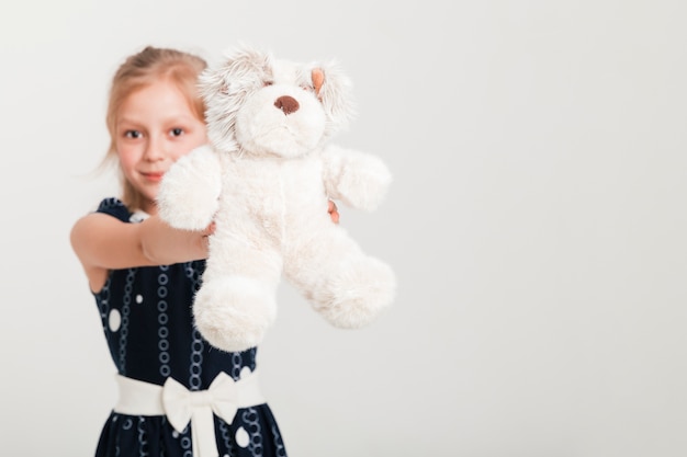 Photo gratuite petite fille montrant son ours en peluche