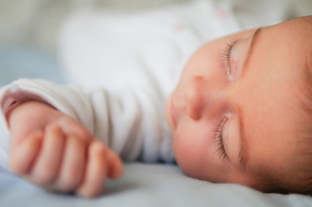 Petite fille nouveau-née dormant sur des draps bleus à la maison