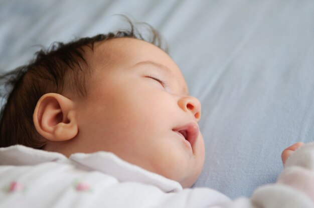 Petite fille nouveau-née dormant sur des draps bleus à la maison