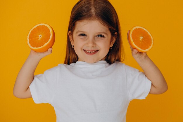 Petite fille avec des oranges isolées en studio