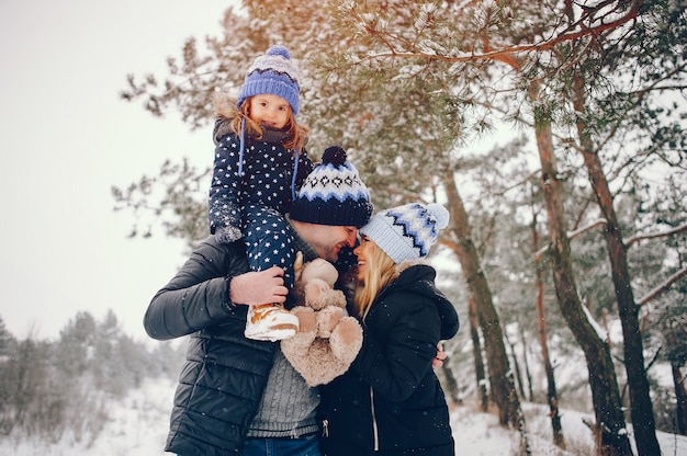 Petite fille avec des parents jouant dans un parc d'hiver