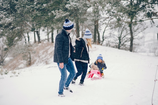 Petite fille avec des parents jouant dans un parc d'hiver