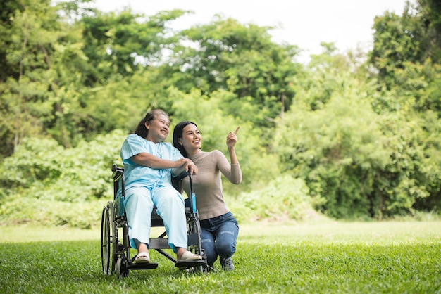 Petite-fille parle avec sa grand-mère assise sur un fauteuil roulant, concept joyeux, famille heureuse