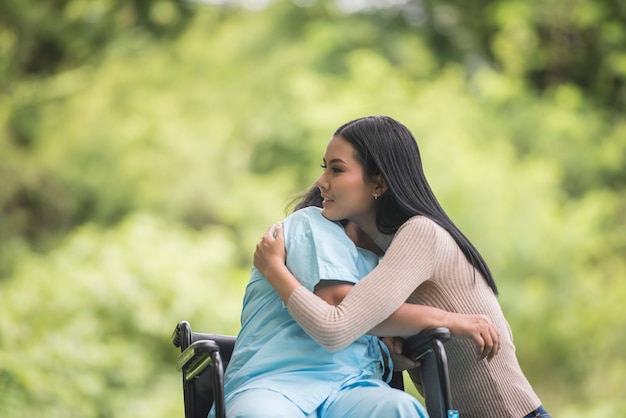 Petite-fille parle avec sa grand-mère assise sur un fauteuil roulant, concept joyeux, famille heureuse