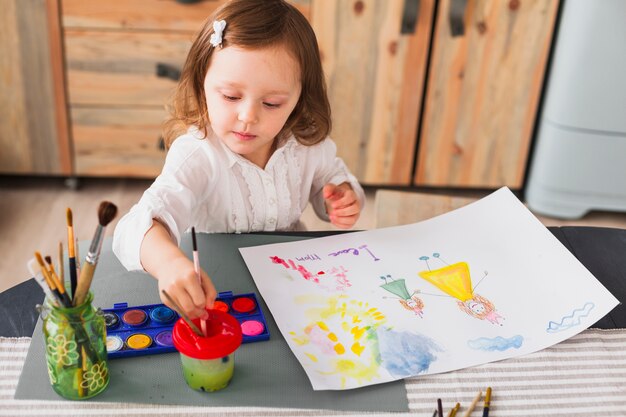 Petite fille peignant mère et enfant sur papier