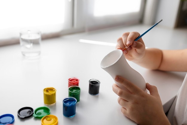 Petite fille peignant un vase à la maison