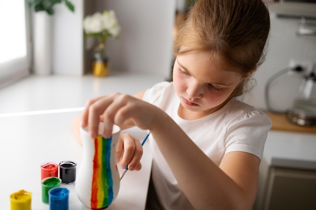 Petite fille peignant un vase à la maison