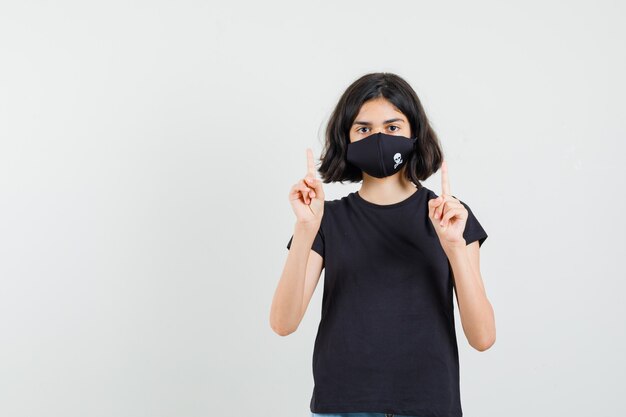 Petite fille pointant vers le haut en t-shirt noir, vue de face du masque.