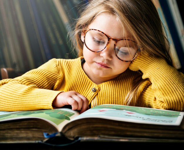 Petite fille portant des lunettes lisant une histoire