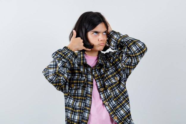 Petite fille posant comme faire un appel téléphonique en chemise, vue de face de la veste.