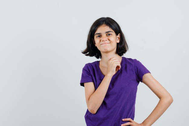 Petite fille posant debout en t-shirt et à la joyeuse