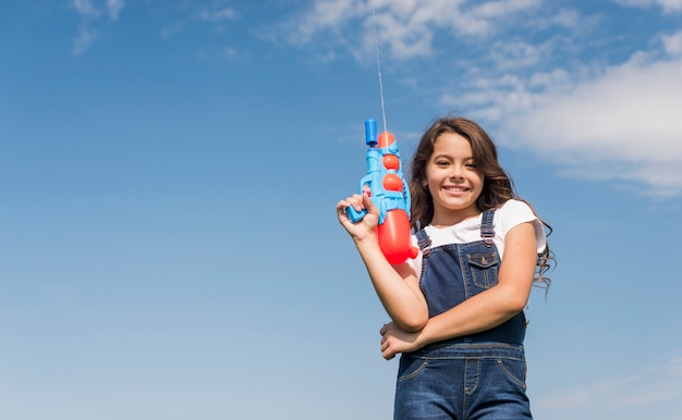 Petite fille posant avec pistolet à eau