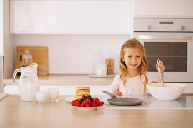 Petite fille préparant des crêpes à la cuisine