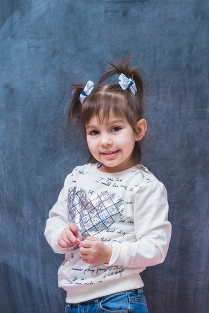 Photo gratuite petite fille avec des queues de mur gris