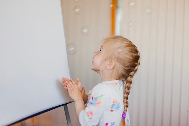 Photo gratuite petite fille regardant des bulles de savon