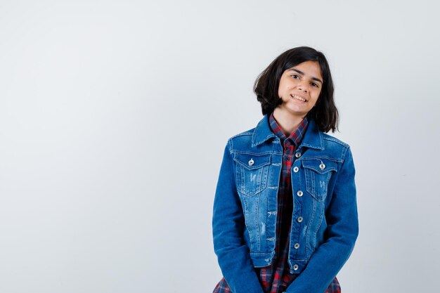 Petite fille regardant la caméra en chemise, veste et l'air confiant, vue de face.