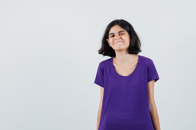 Petite fille regardant la caméra en t-shirt et à la joyeuse.