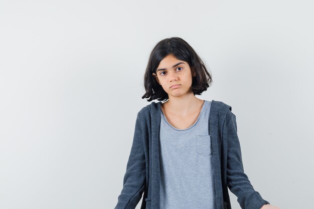 Petite fille regardant la caméra en t-shirt, veste et à la confusion.